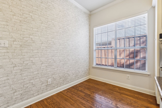 empty room featuring crown molding, dark wood-type flooring, and brick wall