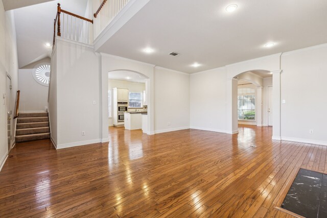 empty room with wood-type flooring, ornate columns, and crown molding