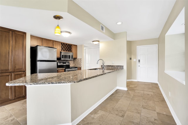 kitchen with appliances with stainless steel finishes, sink, pendant lighting, light tile patterned floors, and decorative backsplash