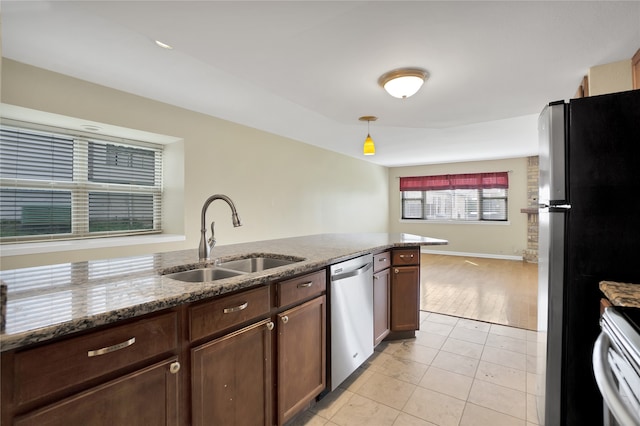 kitchen featuring light tile patterned flooring, decorative light fixtures, stainless steel appliances, sink, and light stone counters