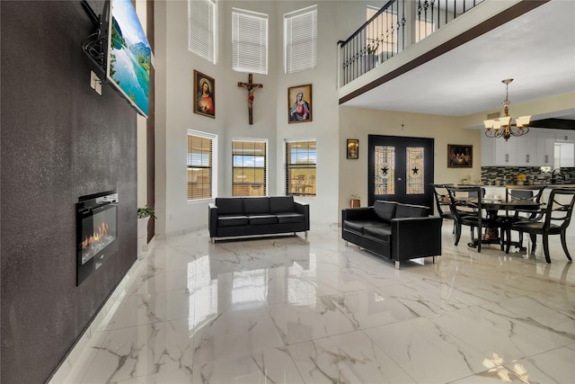 living room with sink, a fireplace, a high ceiling, and an inviting chandelier