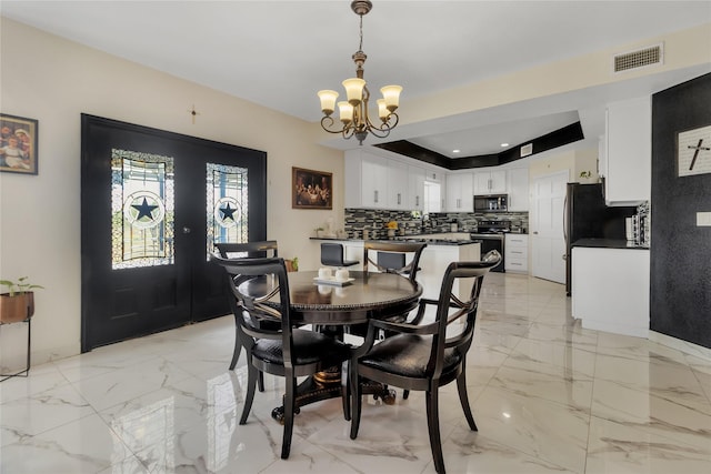 dining room featuring french doors, a tray ceiling, and an inviting chandelier