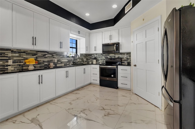 kitchen featuring appliances with stainless steel finishes, backsplash, white cabinetry, and sink