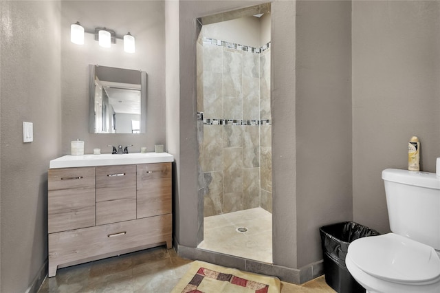 bathroom with toilet, a tile shower, and vanity