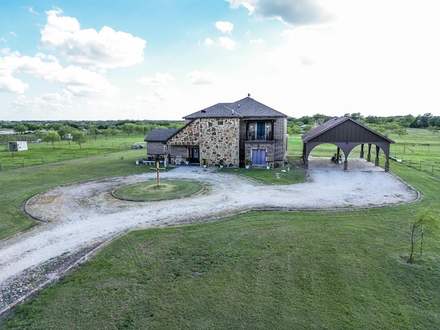 rear view of property with a rural view, an outdoor structure, and a lawn