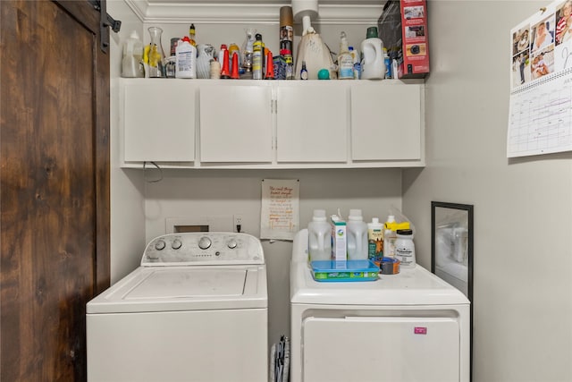 washroom with cabinets, independent washer and dryer, and a barn door