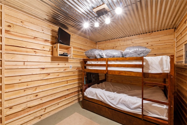 unfurnished bedroom featuring concrete floors, wooden ceiling, and wooden walls