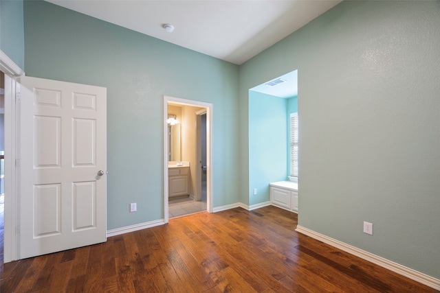 unfurnished bedroom with hardwood / wood-style floors and ensuite bath