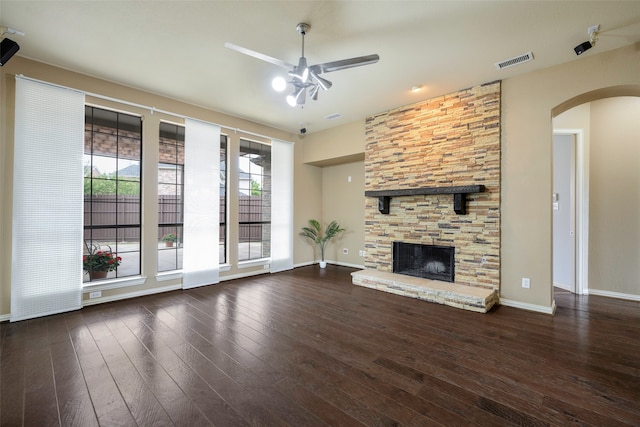 unfurnished living room with ceiling fan, dark wood-type flooring, and a stone fireplace