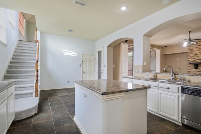 kitchen with white cabinetry, sink, a kitchen island, stainless steel dishwasher, and stone counters