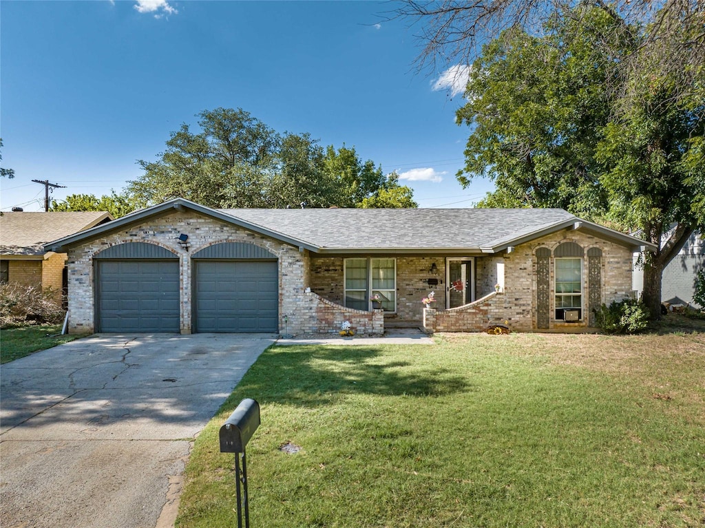 ranch-style house featuring a front yard, concrete driveway, brick siding, and an attached garage