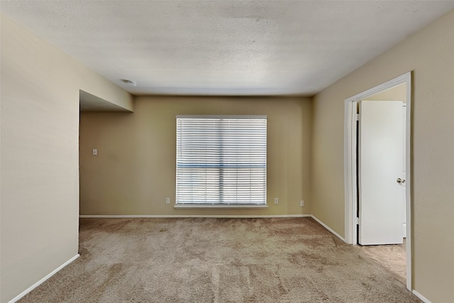 empty room with light colored carpet and a textured ceiling