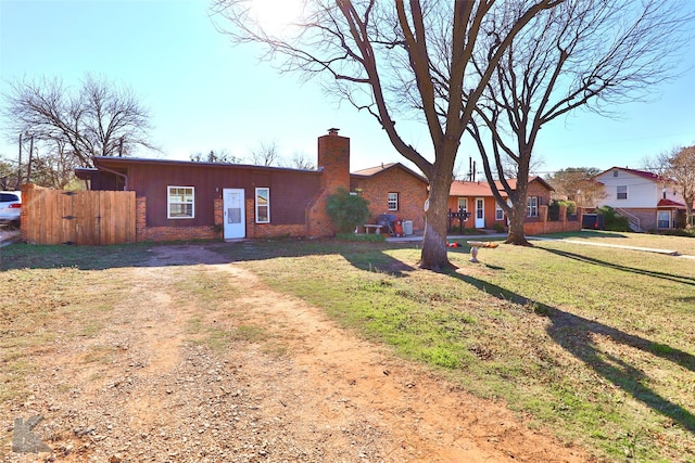 single story home featuring driveway, a chimney, a front lawn, and brick siding