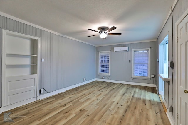 unfurnished room with light hardwood / wood-style flooring, a textured ceiling, built in features, ceiling fan, and a wall unit AC