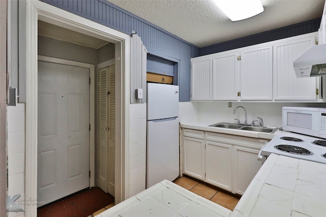 kitchen featuring sink, a textured ceiling, white appliances, and white cabinetry