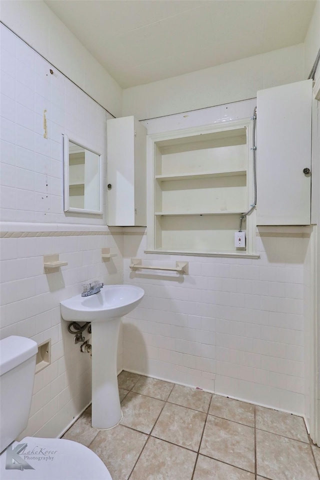 bathroom with tile patterned floors, toilet, and tile walls