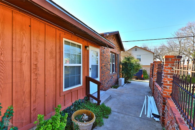 view of property exterior with board and batten siding, a patio area, fence, and central air condition unit