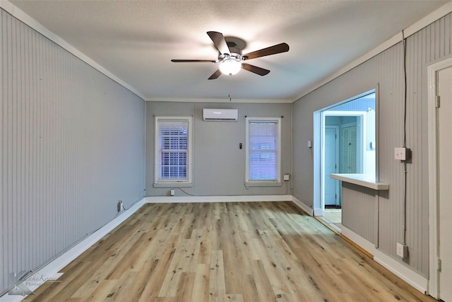 interior space featuring ceiling fan, a wall mounted air conditioner, light wood-style flooring, and baseboards