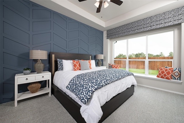 carpeted bedroom with a tray ceiling and ceiling fan