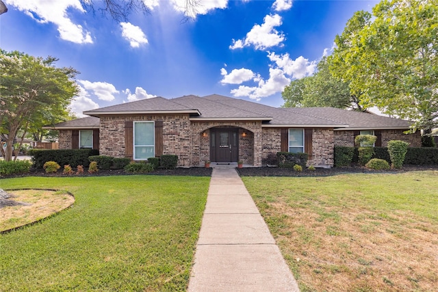 ranch-style home with brick siding, a shingled roof, and a front lawn
