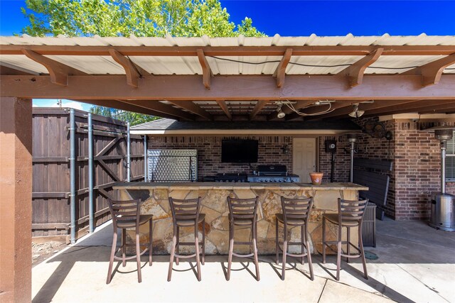 view of patio with outdoor wet bar and fence