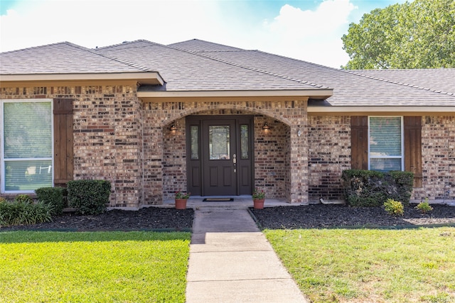 view of exterior entry with a lawn