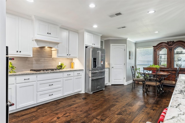 kitchen with crown molding, custom range hood, appliances with stainless steel finishes, dark wood finished floors, and visible vents