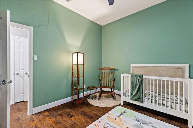 bedroom featuring baseboards, visible vents, a ceiling fan, a crib, and wood finished floors