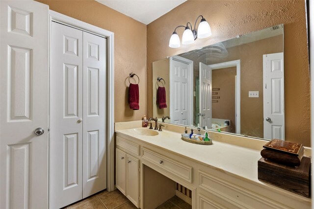 bathroom featuring tile patterned floors, vanity, a textured wall, and a closet