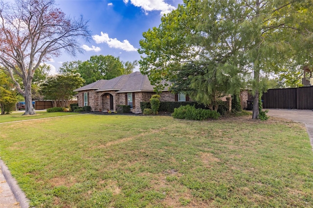 view of front of property with a front lawn, fence, brick siding, and concrete driveway
