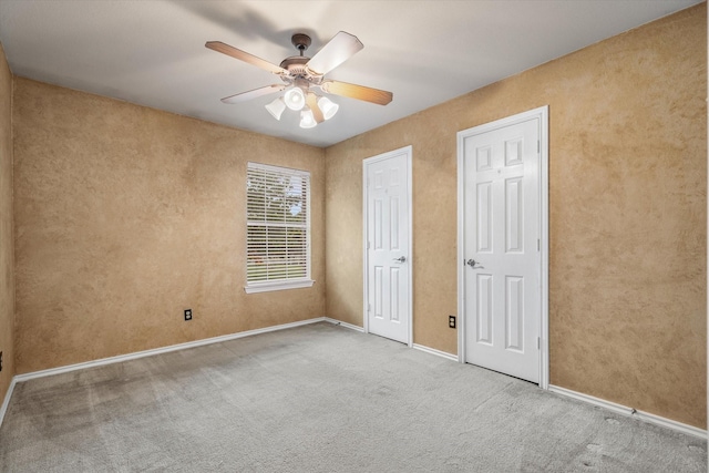 unfurnished bedroom with ceiling fan, two closets, and carpet floors