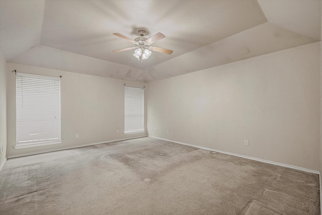 spare room featuring ceiling fan, light carpet, a raised ceiling, and vaulted ceiling