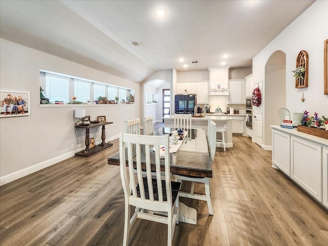 dining room with light hardwood / wood-style floors and vaulted ceiling