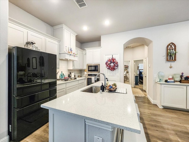 kitchen featuring decorative backsplash, stainless steel appliances, a kitchen island with sink, sink, and white cabinets