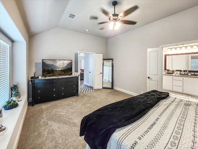 carpeted bedroom featuring ceiling fan, lofted ceiling, and ensuite bath