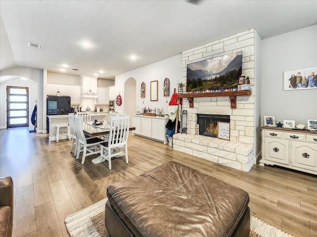 living room with light hardwood / wood-style floors, lofted ceiling, and a fireplace