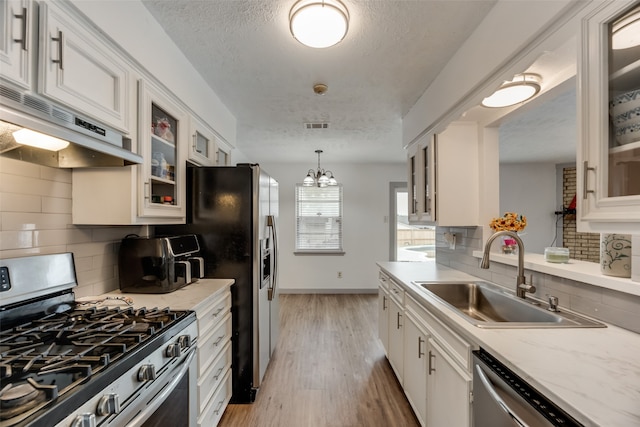 kitchen with white cabinets, sink, appliances with stainless steel finishes, light hardwood / wood-style flooring, and backsplash