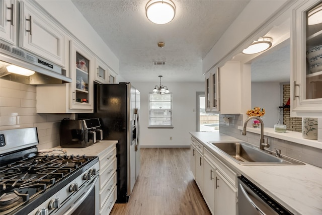 kitchen featuring sink, light hardwood / wood-style flooring, appliances with stainless steel finishes, white cabinetry, and backsplash