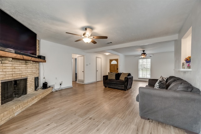 living room featuring brick wall, a brick fireplace, ceiling fan, and light wood-type flooring