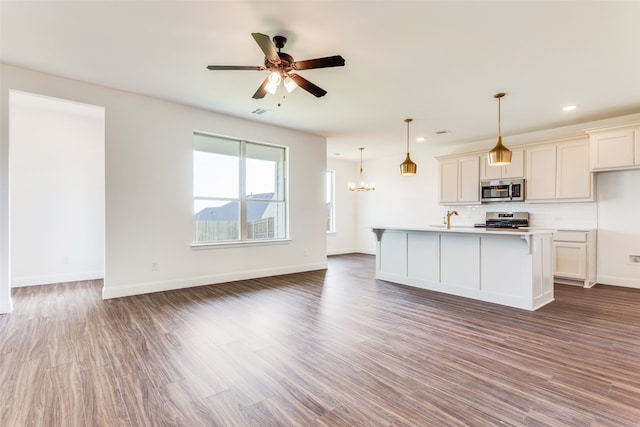 kitchen featuring range, backsplash, wood-type flooring, and a center island with sink