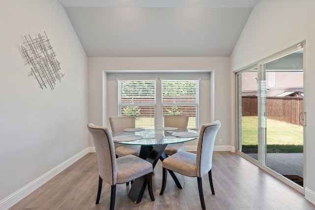 dining area with hardwood / wood-style flooring and vaulted ceiling