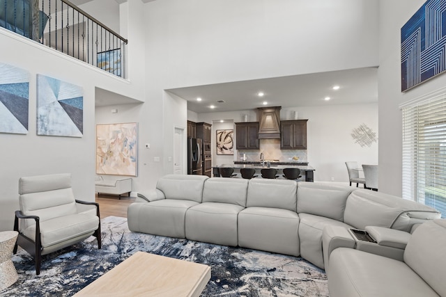 living room featuring sink, hardwood / wood-style floors, and a towering ceiling