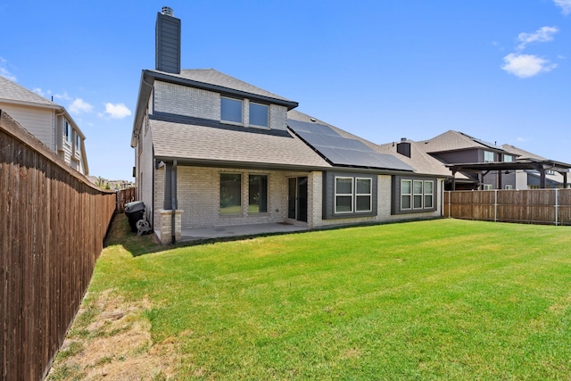 rear view of house featuring solar panels, a patio, and a lawn