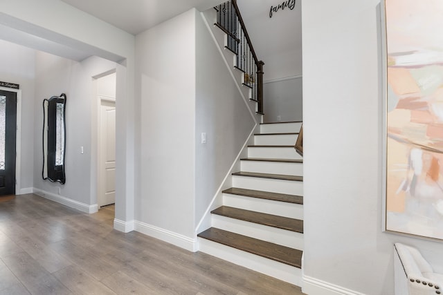 stairs featuring radiator heating unit and wood-type flooring