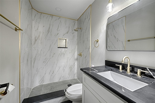 bathroom with a textured wall, a stall shower, vanity, and toilet