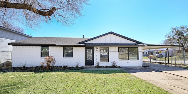 view of front of house with brick siding, fence, concrete driveway, a carport, and a front yard