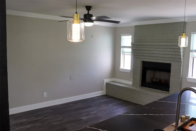 unfurnished living room with dark wood-type flooring, ceiling fan, a brick fireplace, brick wall, and ornamental molding