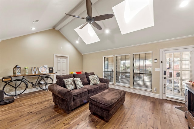 living room with hardwood / wood-style flooring, ceiling fan, vaulted ceiling with skylight, and crown molding