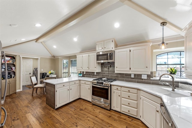 kitchen with white cabinetry, sink, hanging light fixtures, stainless steel appliances, and lofted ceiling with beams