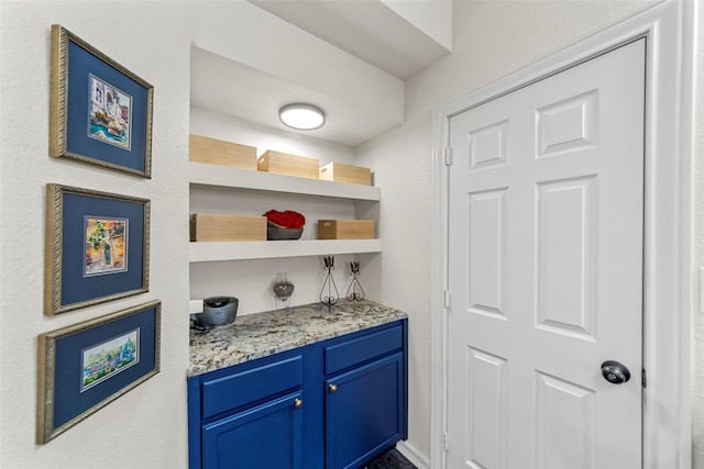 bar featuring light stone countertops and blue cabinets